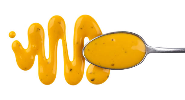 istock Honey mustard sauce. Splashes and spilled salad dressing with spoon isolated on white background. Top view 963845134