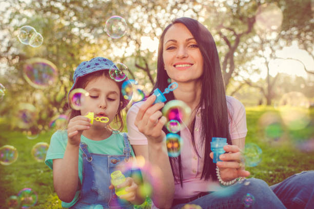 istock Happy mother and daughter blowing bubbles in the park 963854698