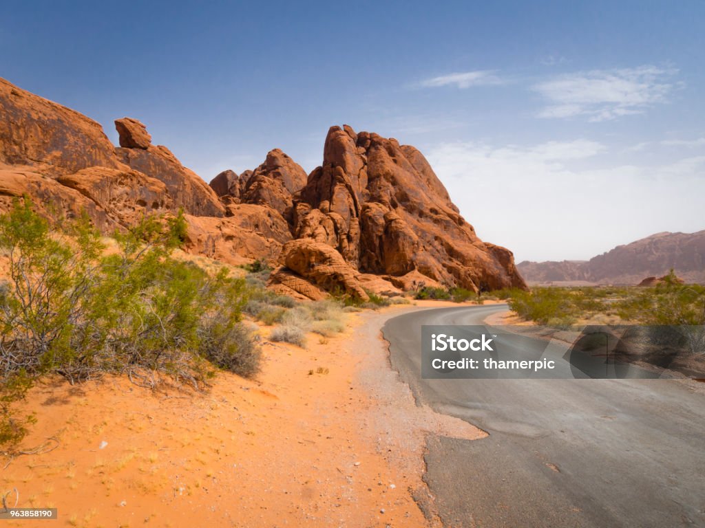 Empty road in the desert Red sandstone rock formations and an empty road in the desert of the Valley of Fire State Park (Nevada, USA). Accidents and Disasters Stock Photo