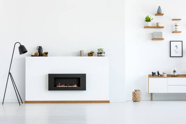 istock Black lamp next to fireplace in white apartment interior with copy space. Real photo 963858644