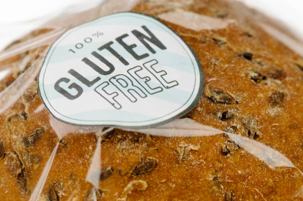 "100% gluten free" sticker on a loaf of brown seeded bread. - gluten allergy imagens e fotografias de stock