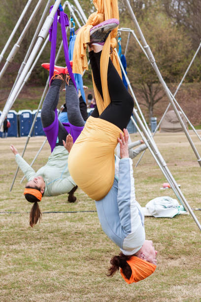 jeunes femmes pendent à l’envers dans les cours de yoga aérien d’atlanta - stretching yoga exercise mat women photos et images de collection