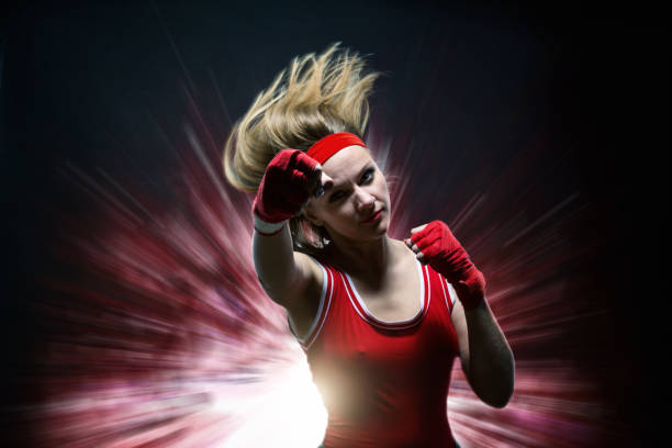 istock Female kickboxer in boxing bandages makes punch 963877644