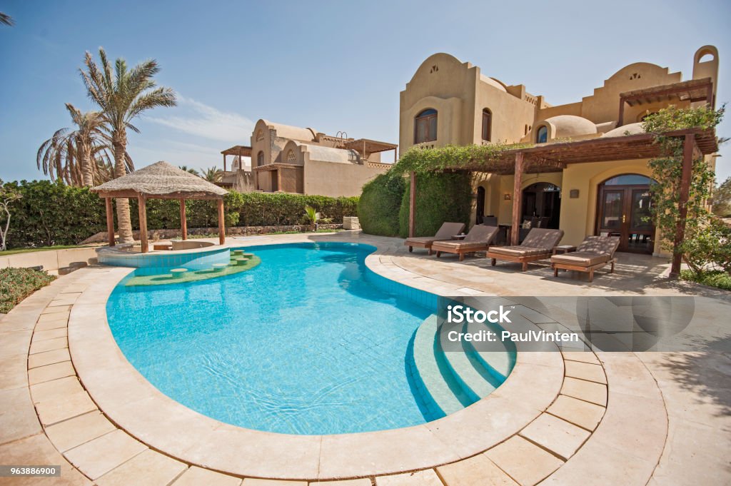 Swimming pool at at luxury tropical holiday villa resort Luxury villa show home in tropical summer holiday resort with swimming pool bar and sun chairs Swimming Pool Stock Photo