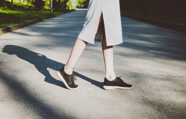 istock Girl crossing road and her figure casting deep dark shadow. 963893436