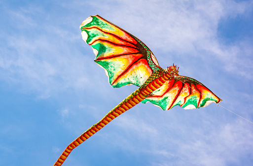 Indonesian kite with an ugly dragon head and a long tail flying in the wind, Sanur, Bali, Indonesia, April 21, 2018