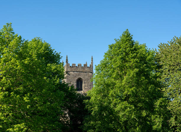 istock Typical english scene of stone church tower between two large trees 963902456