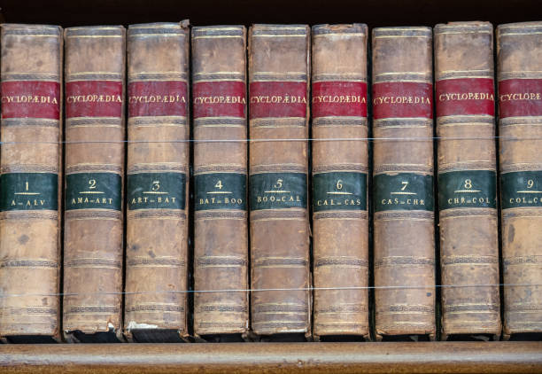 Row of black hardcover books with red labels on their spines, arranged on a wooden shelf in the mayor’s office within the town hall of Ambronay French village. Photo taken in Ambronay, in Ain department, in Auvergne-Rhone-Alpes region in France.