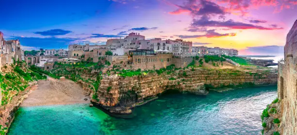 Polignano a Mare, Puglia, Italy: Sunset at Cala Paura gulf with Bastione di Santo Stefano and Lama Monachile beach in background, Apulia, Italy, province of Bari