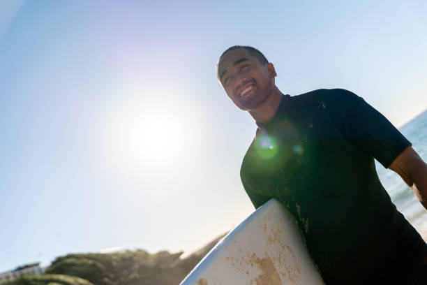 istock Handsome surfer carrying his board and looking very happy 963908362