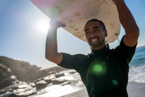 istock Handsome surfer carrying his board and looking very happy 963908468