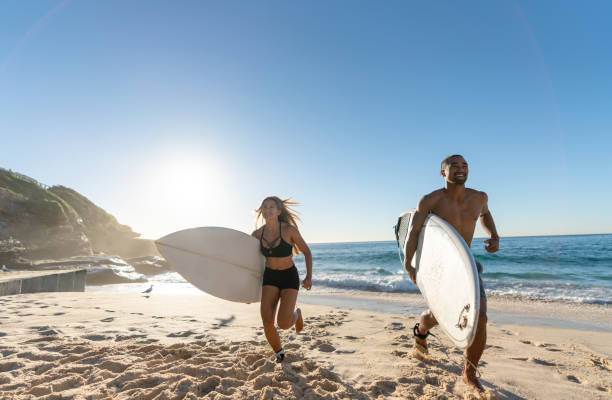 istock Happy couple at the beach surfing and having fun 963908582