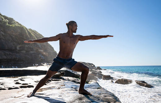 Athletic man doing yoga by the sea and looking very peaceful - meditation concepts