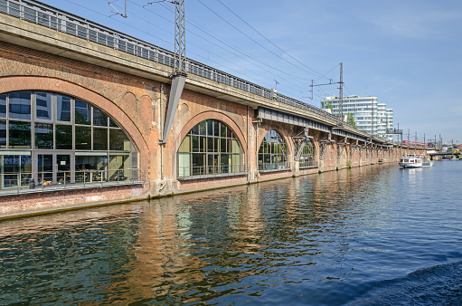 A Stadtbahn viaduct with incoming train, tourist boat and the Trias Towers in Berlin