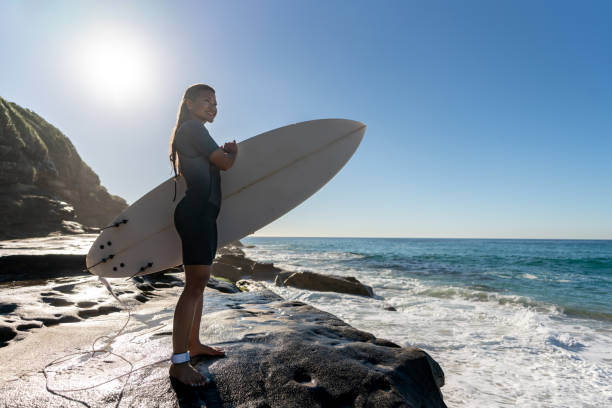 istock Woman at the beach holding a surfboard 963911426