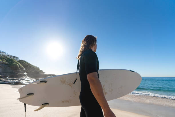 istock Man at the beach surfing and holding a board 963911506