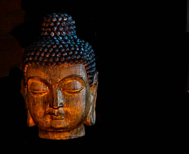 istock Wooden Carved Buddhist Head with Black Background in candlelight 963917182