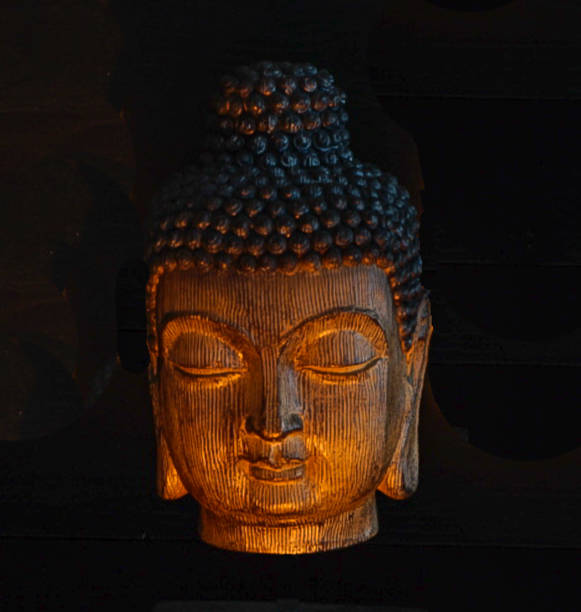 istock Wooden Carved Buddhist Head with Black Background in candlelight 963917198