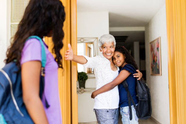 istock Affectionate latin grandma hugging granddaughters after school 963936202