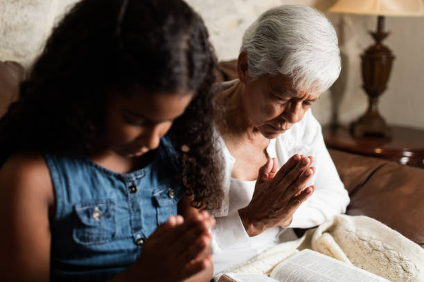 Senior woman and teen girl praying together stock photo