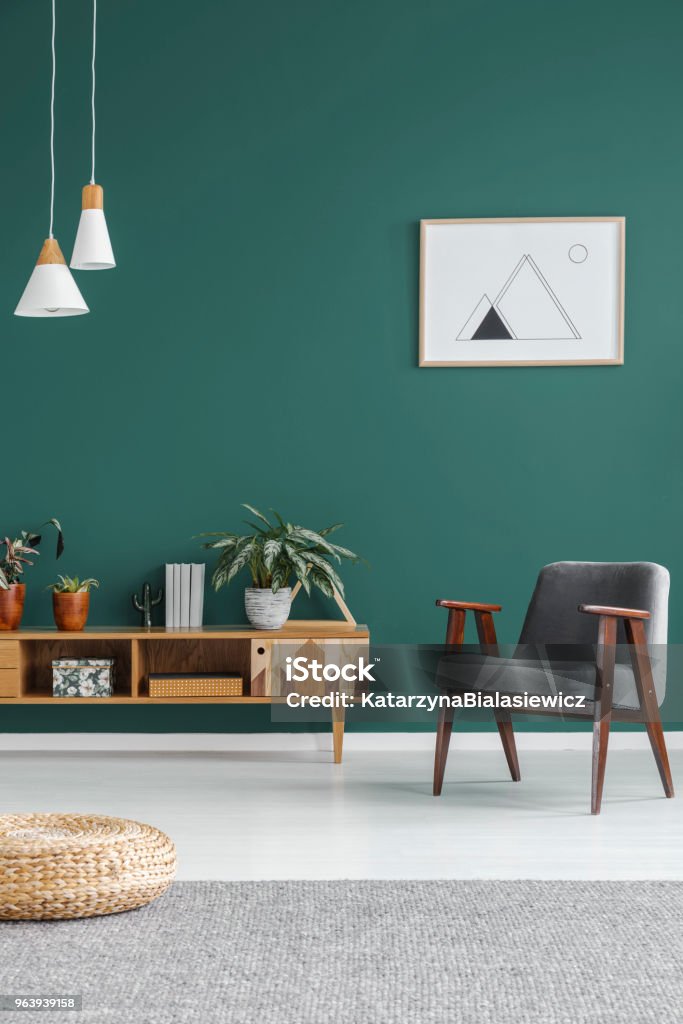 Geometric poster on the wall Simple geometric poster hanging on the wall in green living room interior with grey armchair, wooden cupboard and fresh plants Living Room Stock Photo