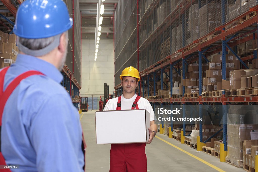 Trabalhador no capacete de segurança uniformizada e carregando caixa - Foto de stock de Adulto royalty-free