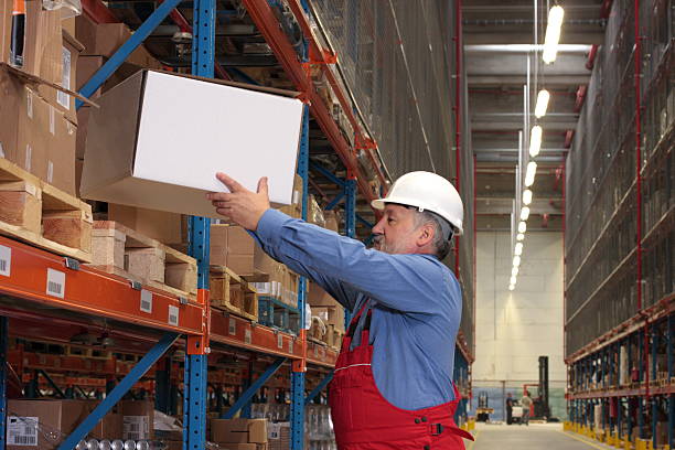 worker  putting box on  shelf in warehouse stock photo