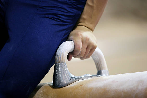 Adults practicing gymnastics on a professional training apparatus with expert guidance and a supportive, energetic group.