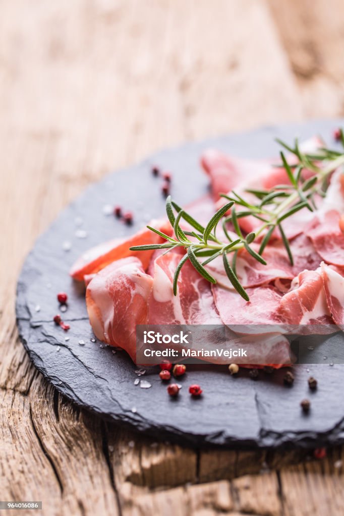 Coppa di Parma ham on slate board with rosemary salt and pepper Coppa di Parma ham on slate board with rosemary salt and pepper. Appetizer Stock Photo