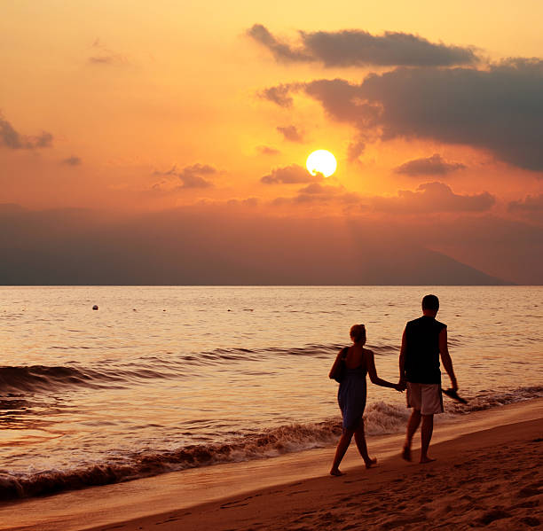 istock Man and a woman taking a beachside stroll at sunset 96402320