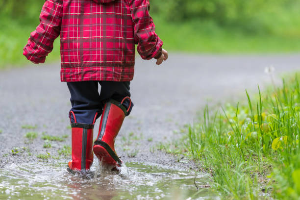 istock Young Cute Kid Walking Jumping into Water Puddle 964023748