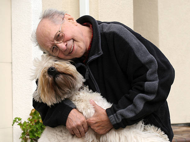 istock An elderly man with glasses smiling and hugging his sheepdog 96402716