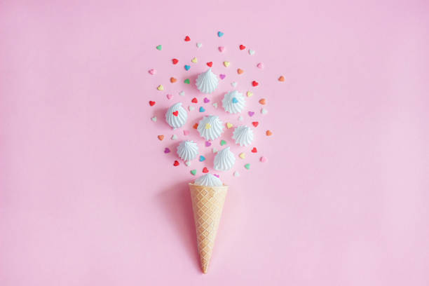 istock waffle cone and white twisted meringue with confectionary decorations on pink background. 964031504