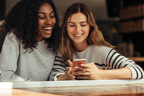 istock Friends sitting in a cafe looking at mobile phone 964049714