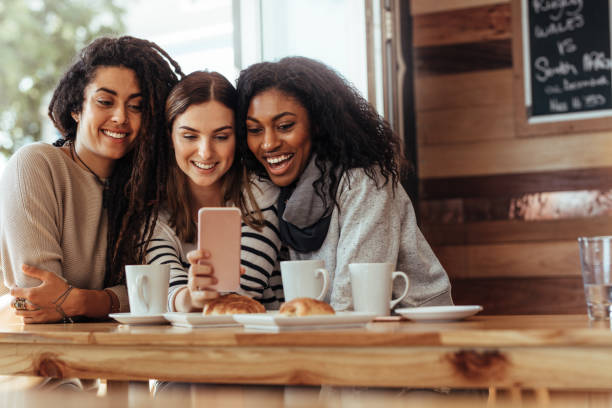 istock Friends sitting in a cafe looking at mobile phone 964050220