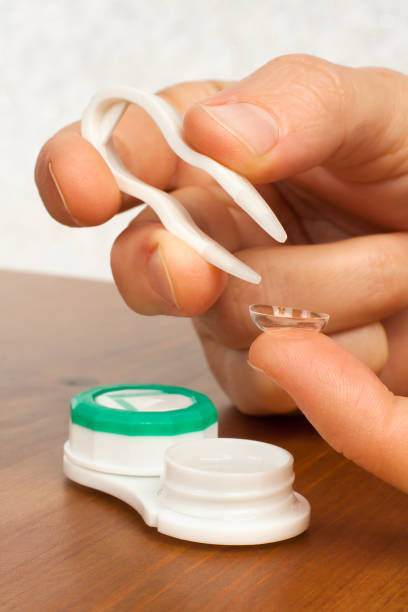 istock hands putting on contact lenses, closeup 964057410