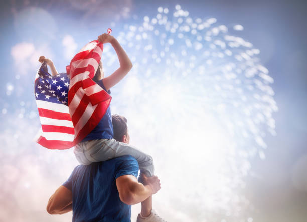 People holding the Flag of the USA. Patriotic holiday. Child sitting on shoulders of her father and holding the Flag of the USA. America celebrate 4th of July. patriotic man stock pictures, royalty-free photos & images