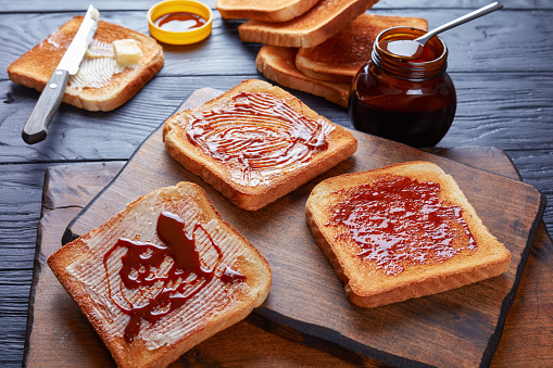 savory toasts for breakfast with butter vegemite - healthy food spread made from leftover brewers yeast extract with vegetables and spices, view from above, close-up