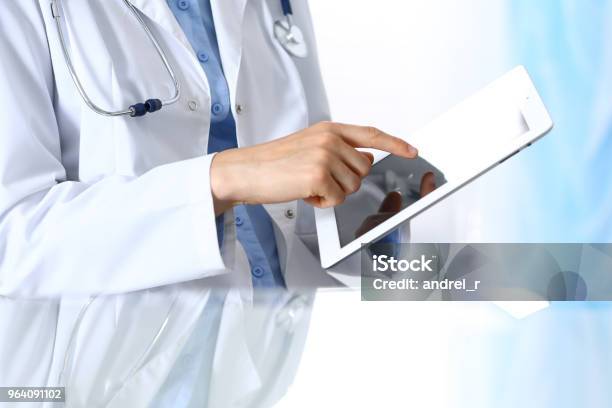 Woman Doctor Using Tablet Computer While Sitting Reflecting Glass Table Is A Working Place Of Physician Healthcare Insurance And Medicine Concept Stock Photo - Download Image Now
