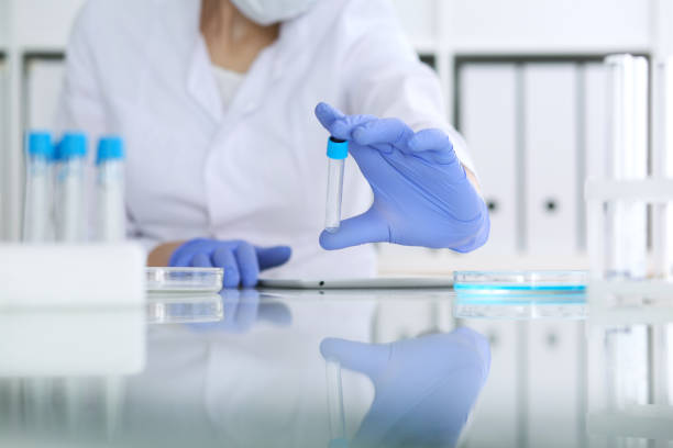 close-up of professional female scientist in protective eyeglasses making experiment with reagents in laboratory. medicine and research concept - close up medical test exam people imagens e fotografias de stock