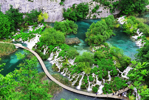 an aerial and panoramic vie of the wooden pathway between the colorful lakes of croatia