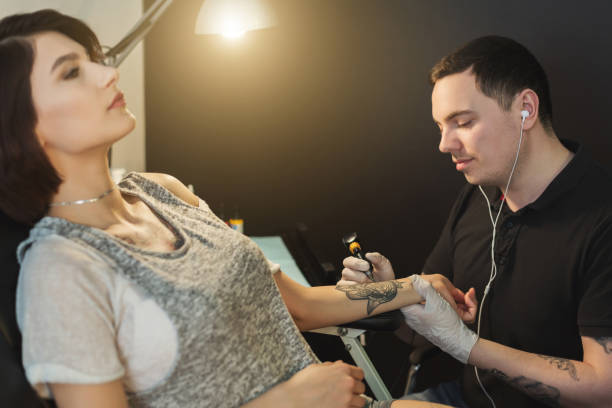 istock Tattoo artist working with needle on clients arm 964092036