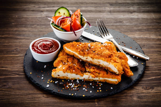 Fried pork chop and vegetables Fried pork chop and vegetables on stone plate schnitzel stock pictures, royalty-free photos & images