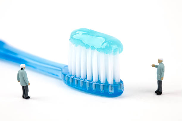 istock two miniature dentists inspecting toothbrush 964116482
