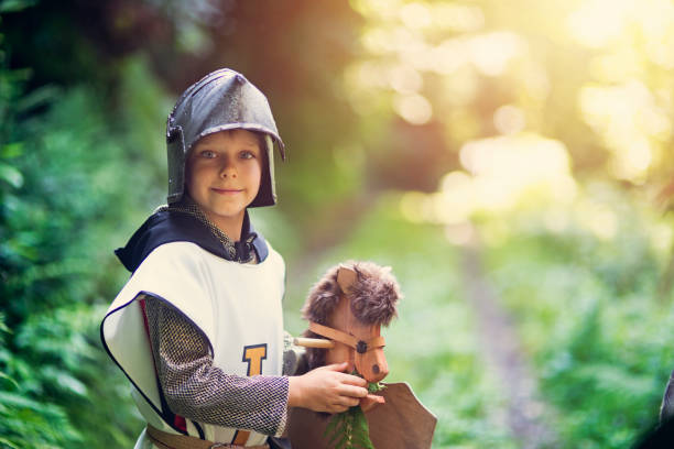 istock Cute little knight feeding his horse in forest 964129100