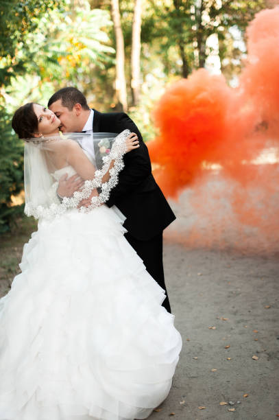 istock Elegant young happy wedding couple is sitting at green grass on 964129906