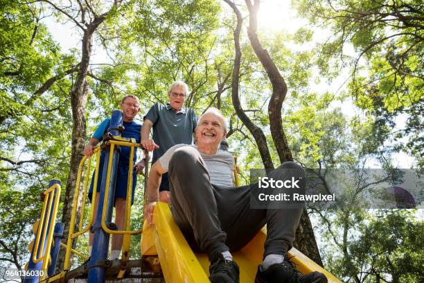 Senior Men Playing At A Playground Slide Stock Photo - Download Image Now - Senior Adult, Playground, Young at Heart