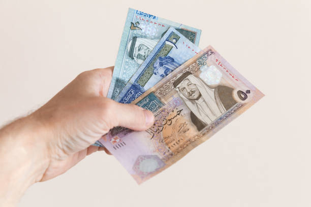 Male hand holding Jordanian dinars Male hand holding Jordanian dinars banknotes over white wall background dinar stock pictures, royalty-free photos & images