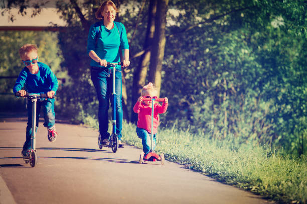 istock mother with kids riding scooters in nature 964143914