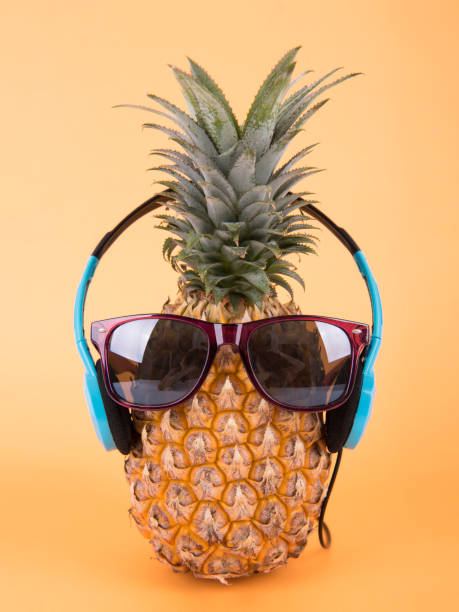 istock Pineapple with sunglasses and headphone on orange background. fruit summer concept. 964147370